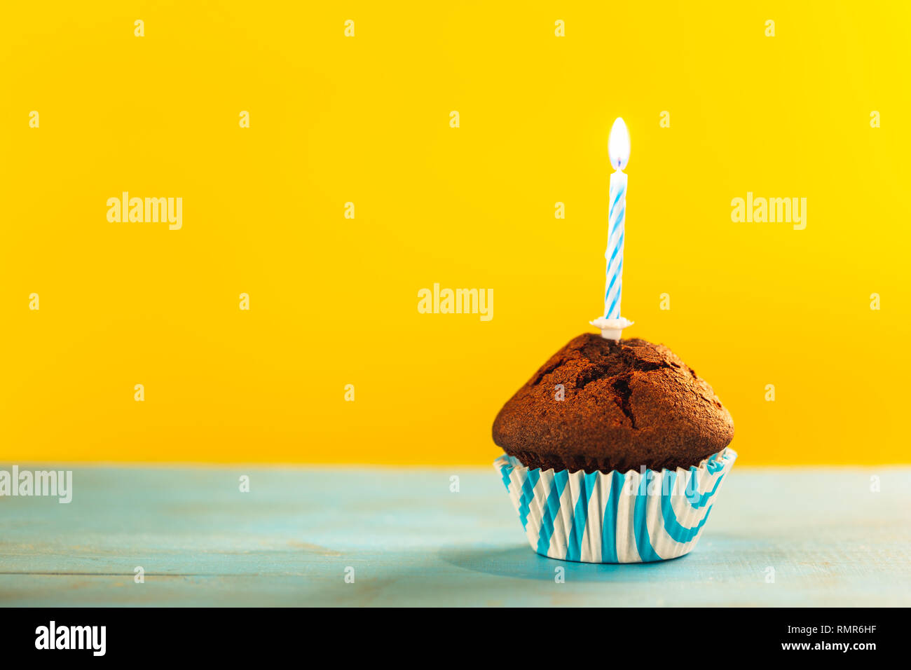 Birthday cupcake avec une seule bougie sur fond jaune et bleu. Banque D'Images