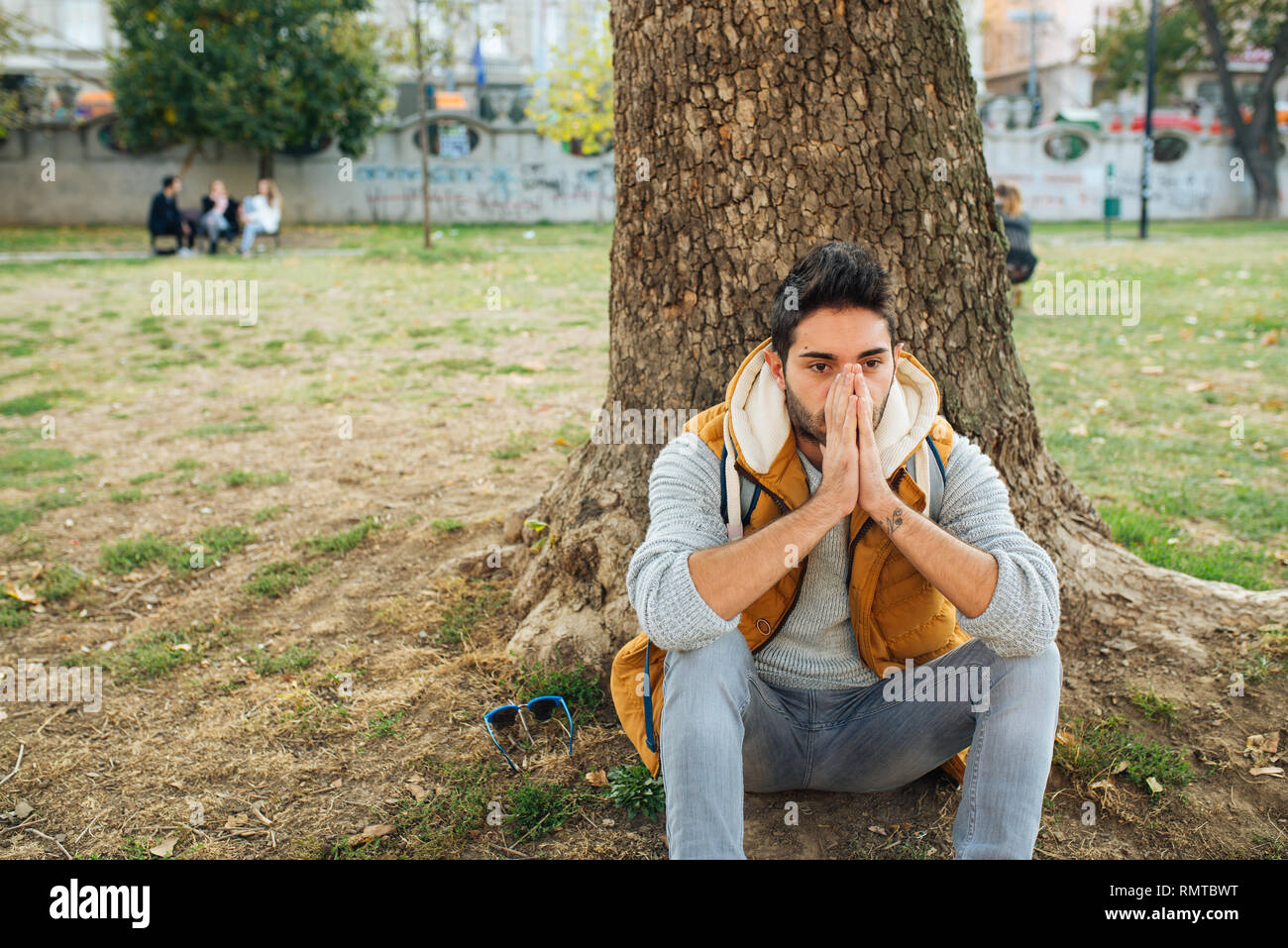 L'homme dépressif assis dans le parc avec hâte et irrité des sentiments. Les émotions négatives.Stress et dépression concept. Banque D'Images