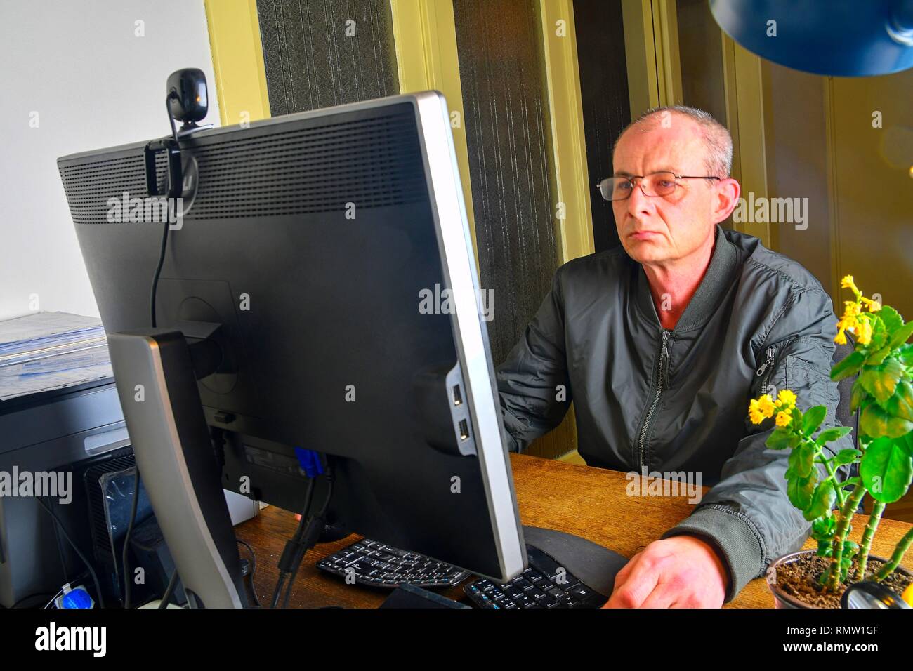 Homme d'âge moyen avec des lunettes assis à un bureau. Homme mûr à l'aide de l'ordinateur personnel. Concept principal Banque D'Images