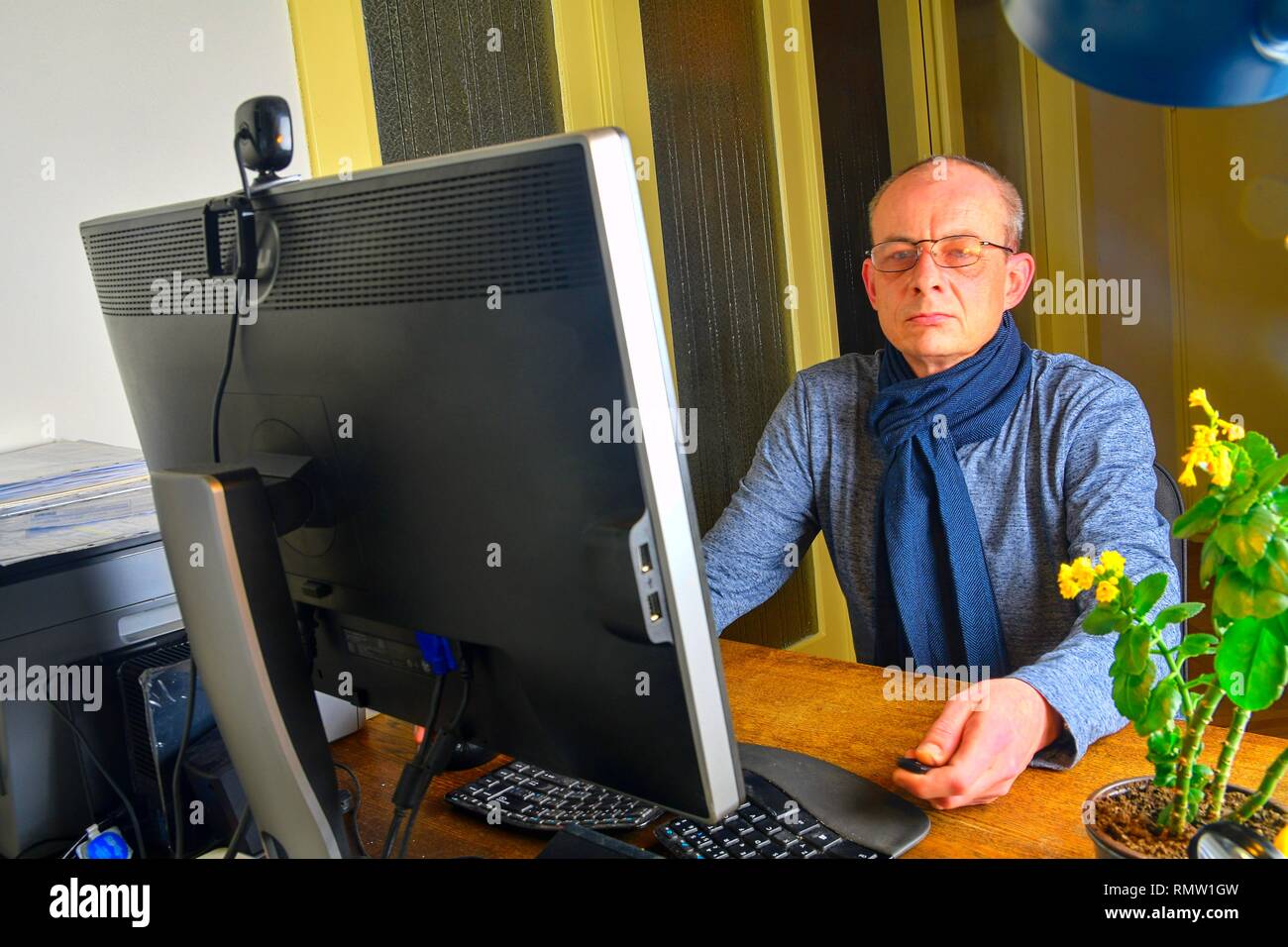 Homme d'âge moyen avec des lunettes assis à un bureau. Homme mûr à l'aide de l'ordinateur personnel. Concept principal. Man working at home office Banque D'Images