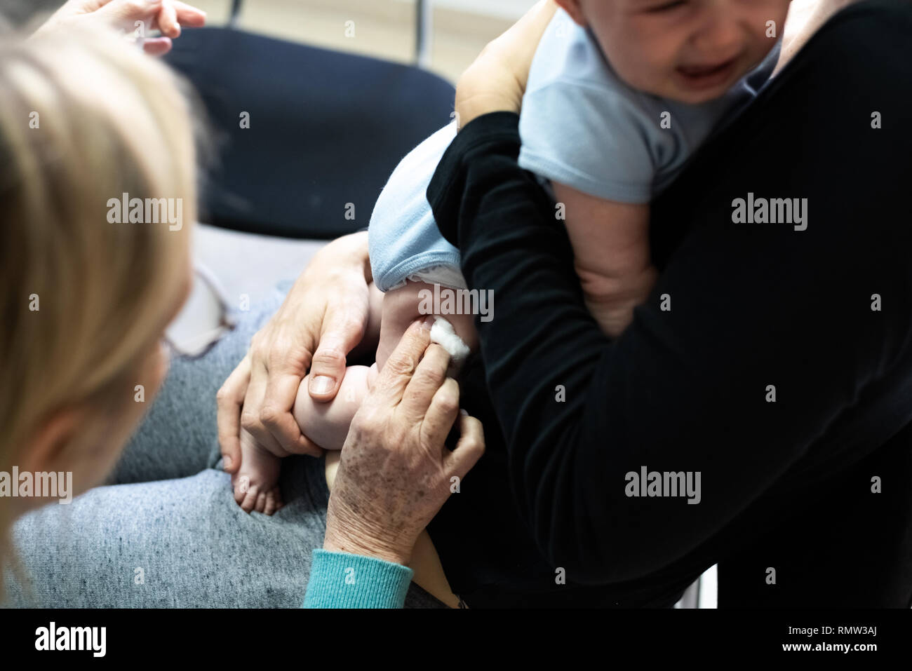 Bebe Qui Pleure Apres La Vaccination Avec L Aide De Bande Ou Le Platre Dans La Cuisse Reconforte Par Sa Mere Qui Allaite Lui Photo Stock Alamy