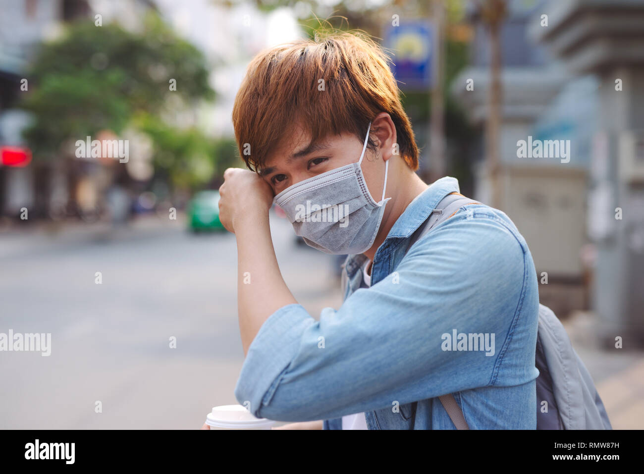 L'homme asiatique dans la rue portant des masques de protection., homme malade avec la grippe wearing mask et blowing nose en serviette comme concept de la grippe épidémique dans la rue. Banque D'Images