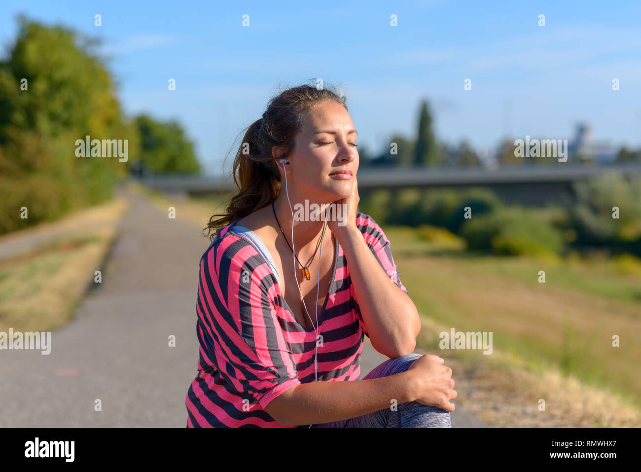 Belle femme à l'écoute de la musique à travers ses écouteurs et jouit de l'instant Banque D'Images