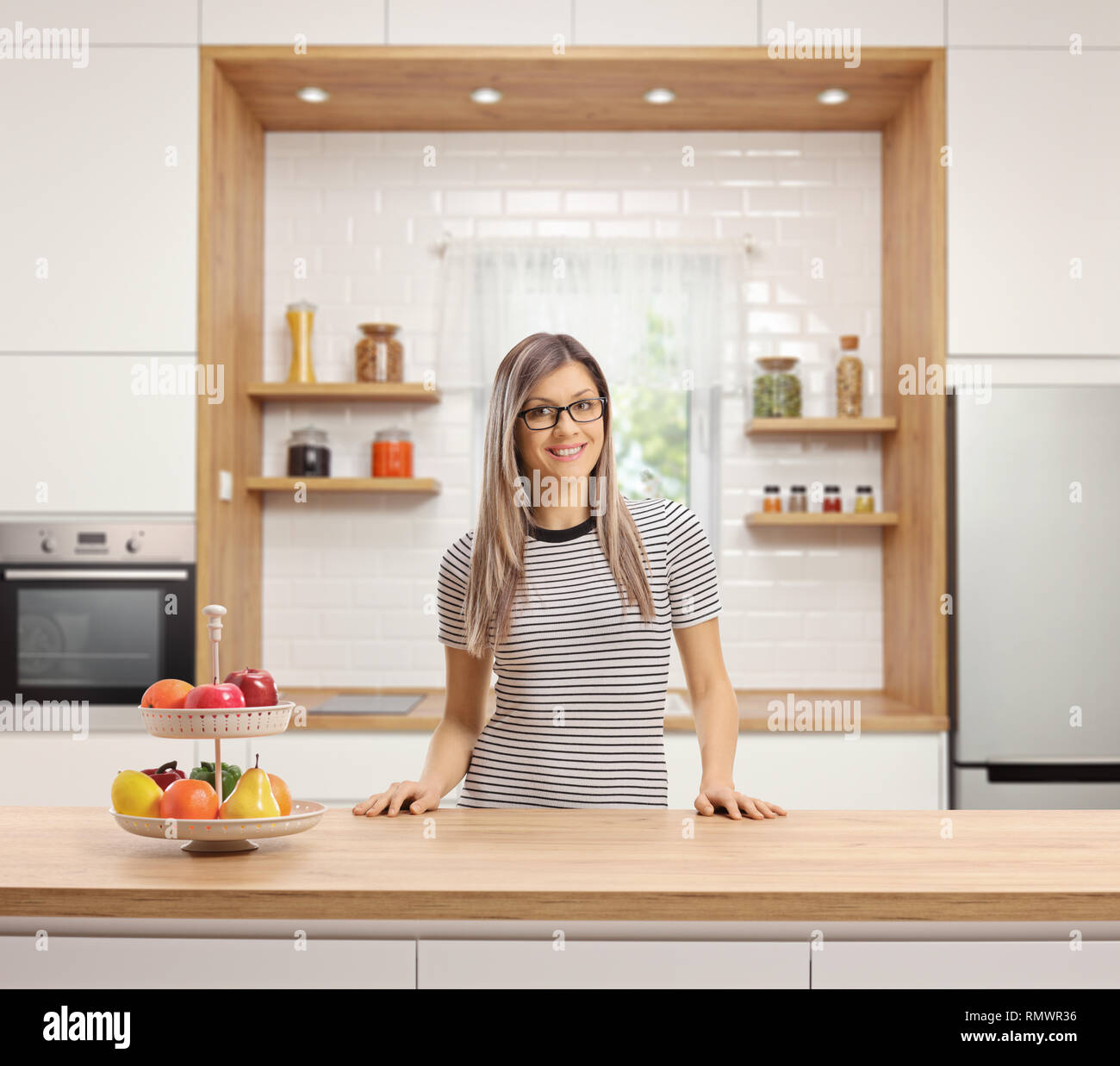 Jeune femme debout derrière un plan de travail en bois dans une cuisine moderne Banque D'Images