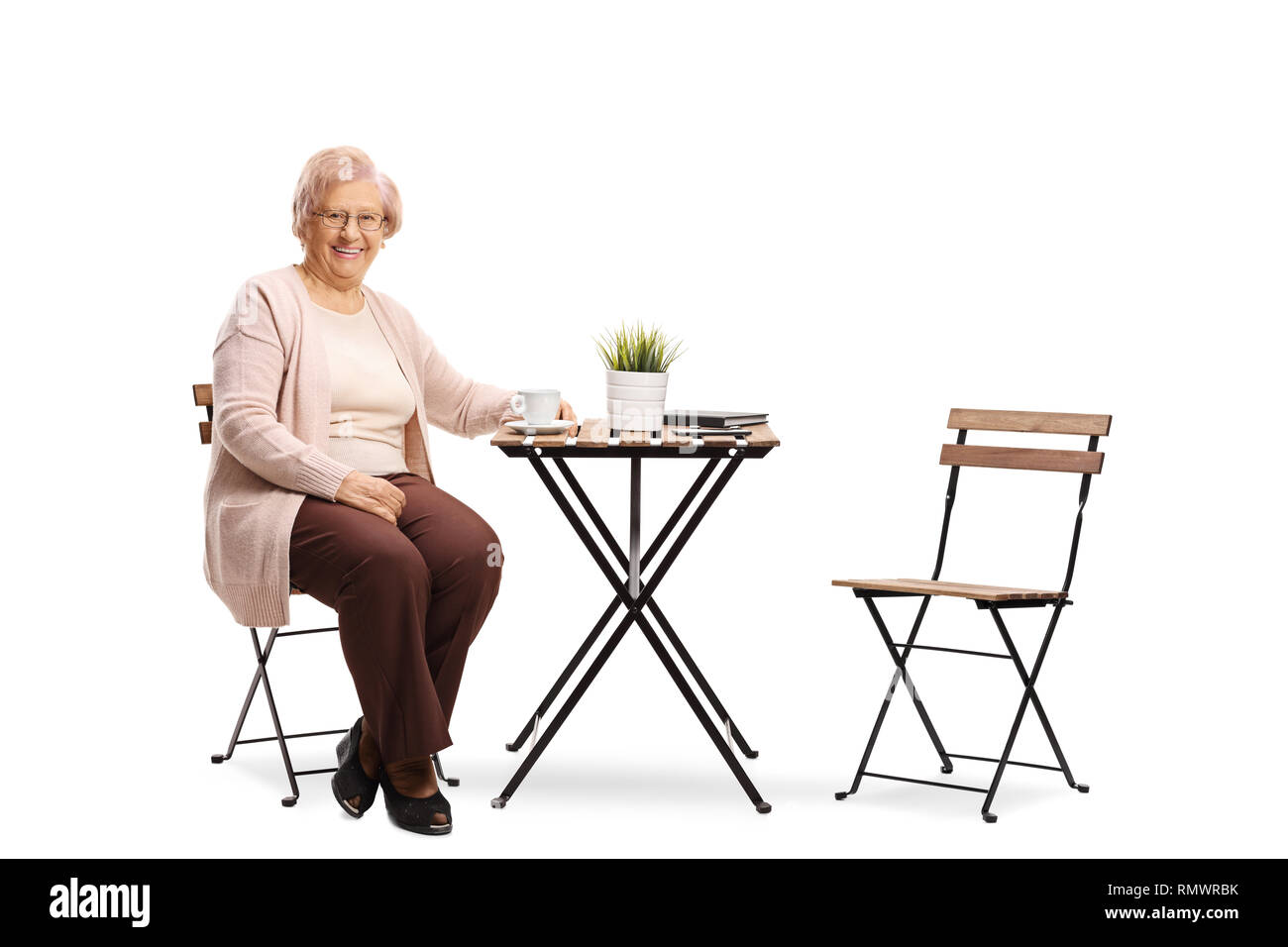 Portrait d'une femme âgée assise à une table avec une tasse de café et souriant à la caméra isolé sur fond blanc Banque D'Images