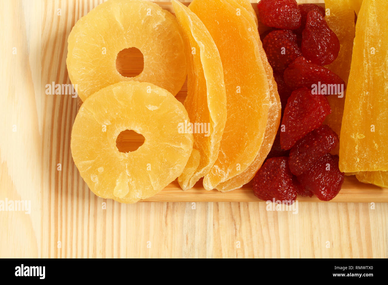 Les morceaux de papaye, mangue, ananas et fraises, allongé sur une plaque de bambou sur une table en bois. Macro. Libre Banque D'Images