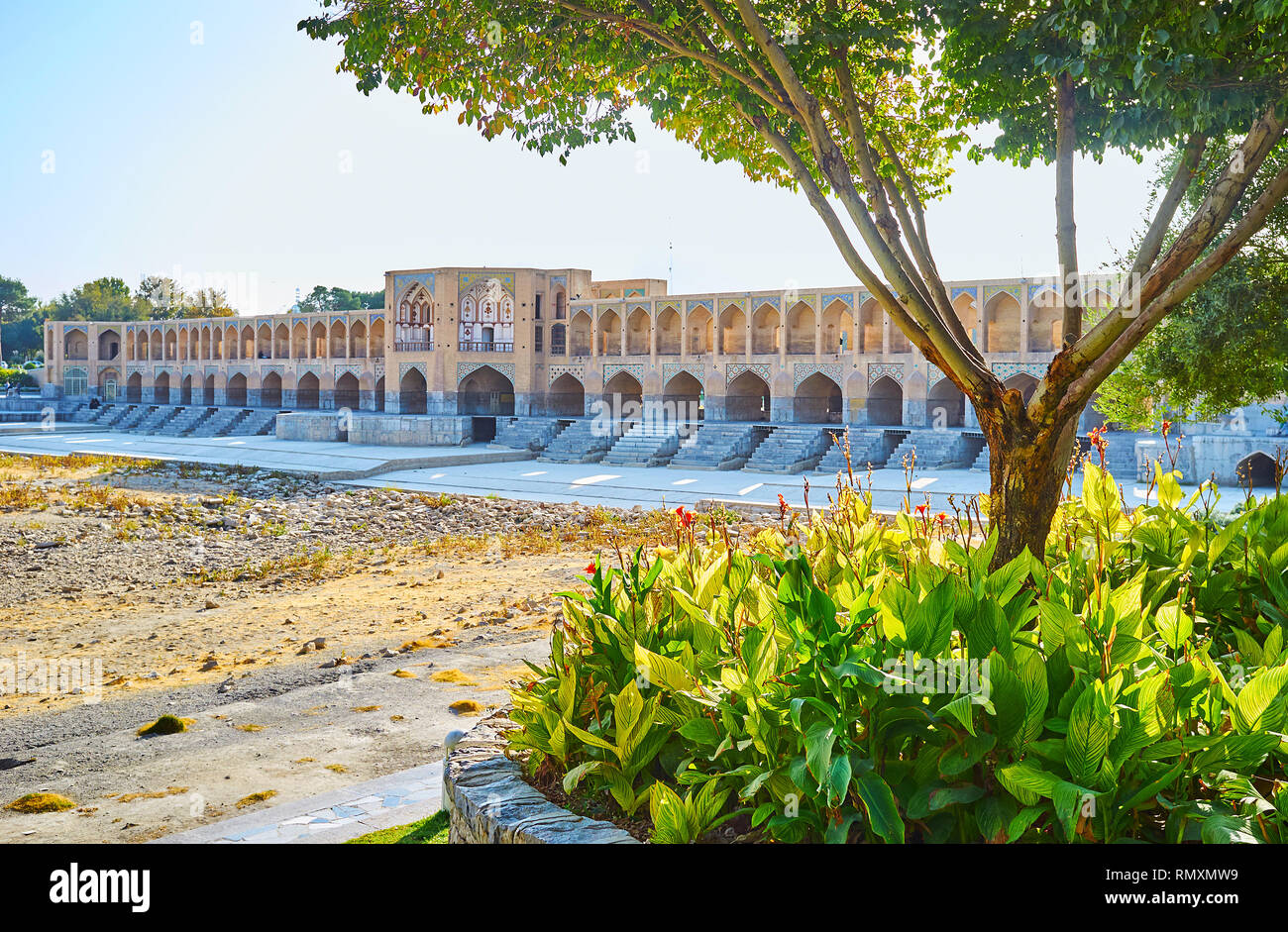 Regardez le pont Khaju brique médiévale et séché Zayanderud rivière à travers la végétation luxuriante de Moshtagh park, Isfahan, Iran. Banque D'Images