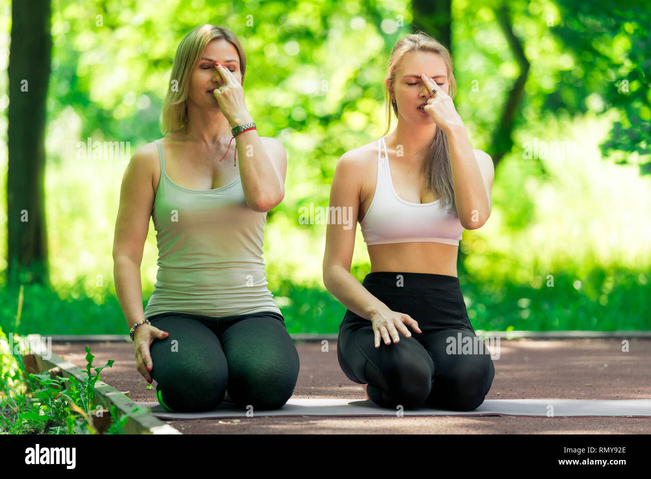 Femme 40 ans avec un formateur, effectuez les exercices de respiration avec un formateur à l'air libre Banque D'Images