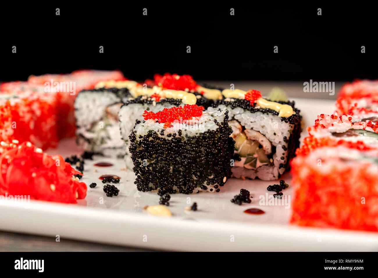 Close up of Philadelphia roule avec du thon, concombre et fromage à la crème, recouvert de caviar noir. Sushi Uramaki situé sur la plaque blanche. Banque D'Images