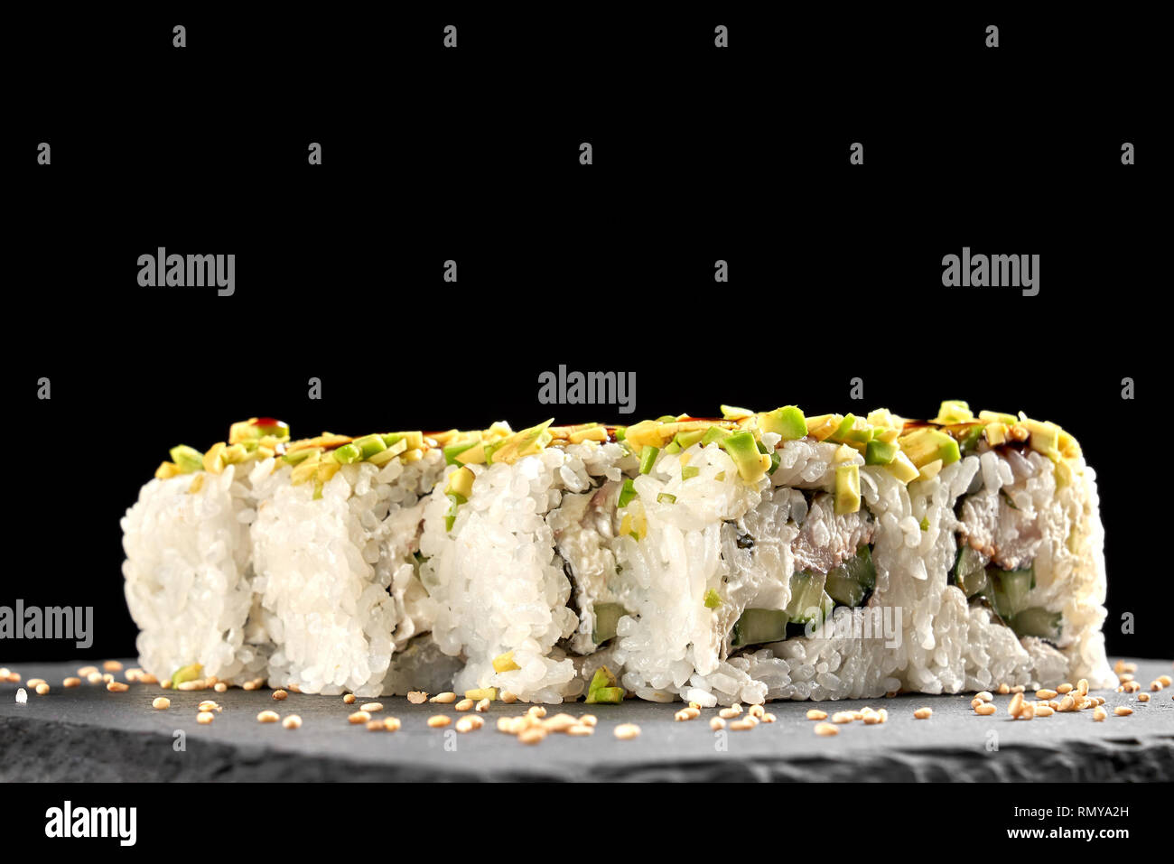 Vue avant du délicieux rouleaux uramaki rempli de concombre, anguille fumé et fromage à la crème. Décorées avec du sésame, présenté sur la plaque d'ardoise. Banque D'Images