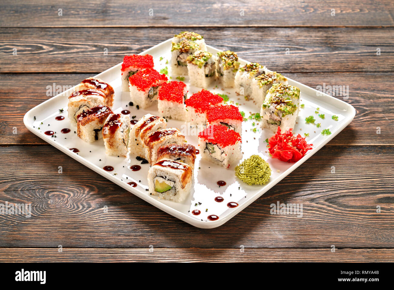 Beau dragon set de sushis, décorées avec sauce unagi, wasabi et gingembre mariné sur plaque blanche. La Californie et philadelphia rolls remplie de fromage à la crème, le concombre, l'anguille fumée et la chair de crabe. Banque D'Images