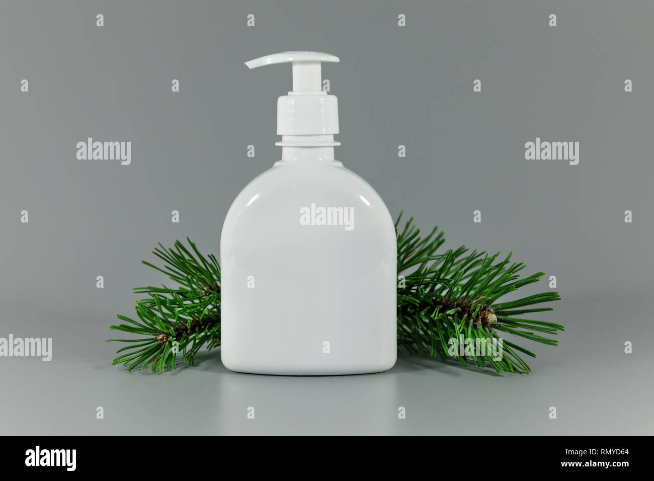 Pompe flacon de parfum blanc vide avec pine tree branch sur fond gris Banque D'Images