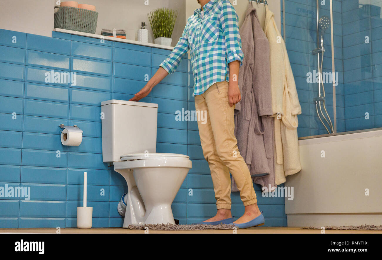 Habillé young caucasian woman vide les toilettes dans la salle de bains moderne, vue de dessous Banque D'Images