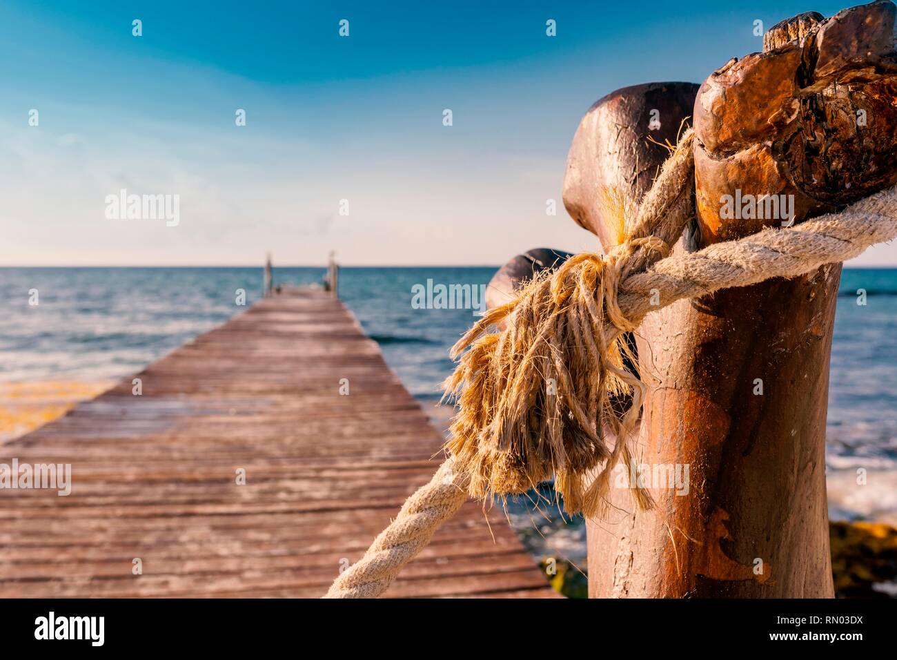 Ancienne jetée en bois rustique à la mer pendant une journée ensoleillée sur la côte des Caraïbes du Mexique avec l'ancienne corde nouée autour de la poste. Banque D'Images