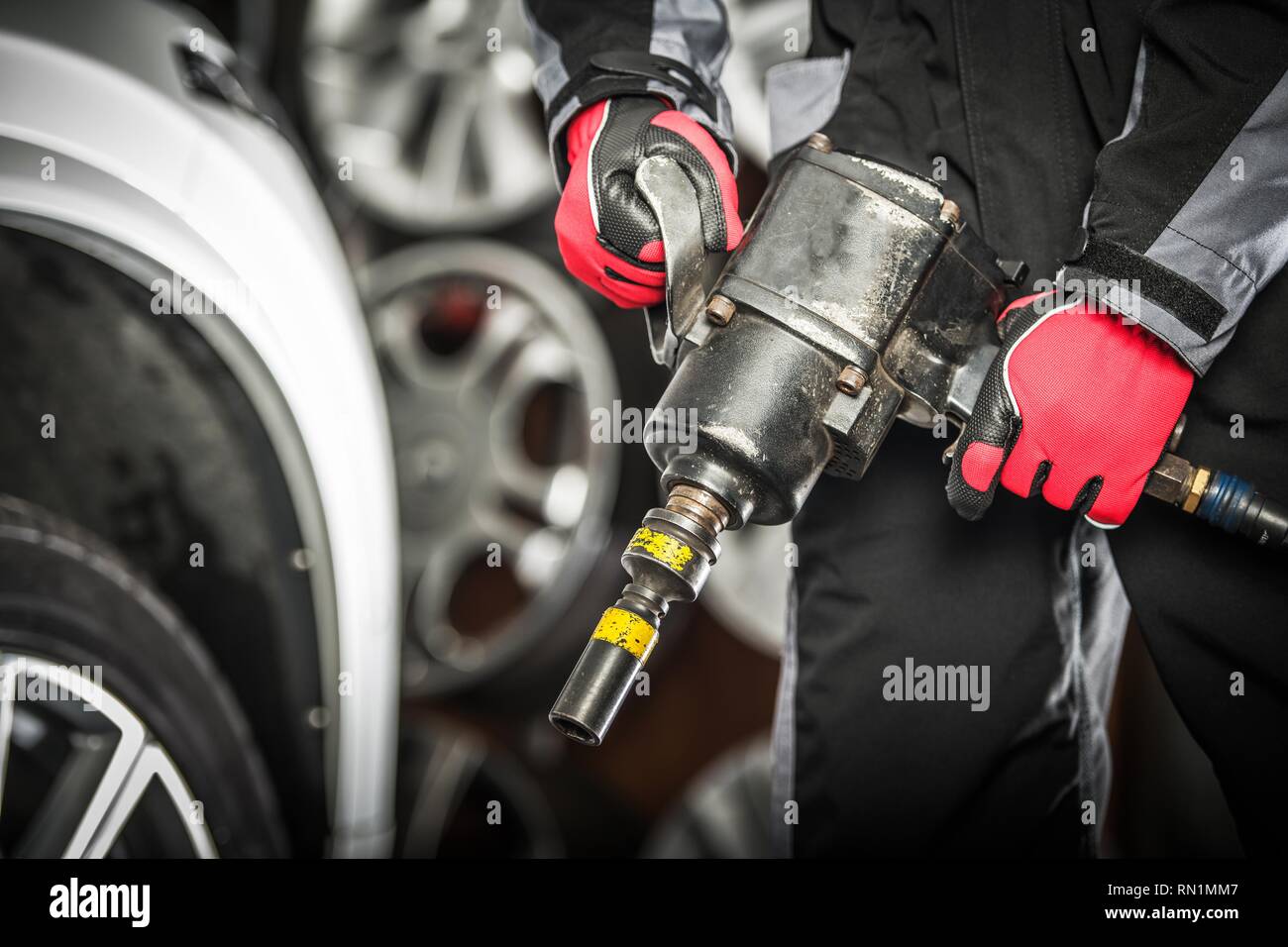 Travailleur des services de l'automobile avec la préparation du pistolet pneumatique pour changer les pneus de saison. Banque D'Images