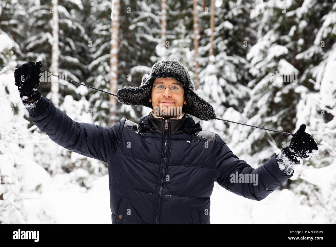 L'homme en hiver fourrure chapeau avec oreilles smiling portrait. Extrême dans la forêt Banque D'Images