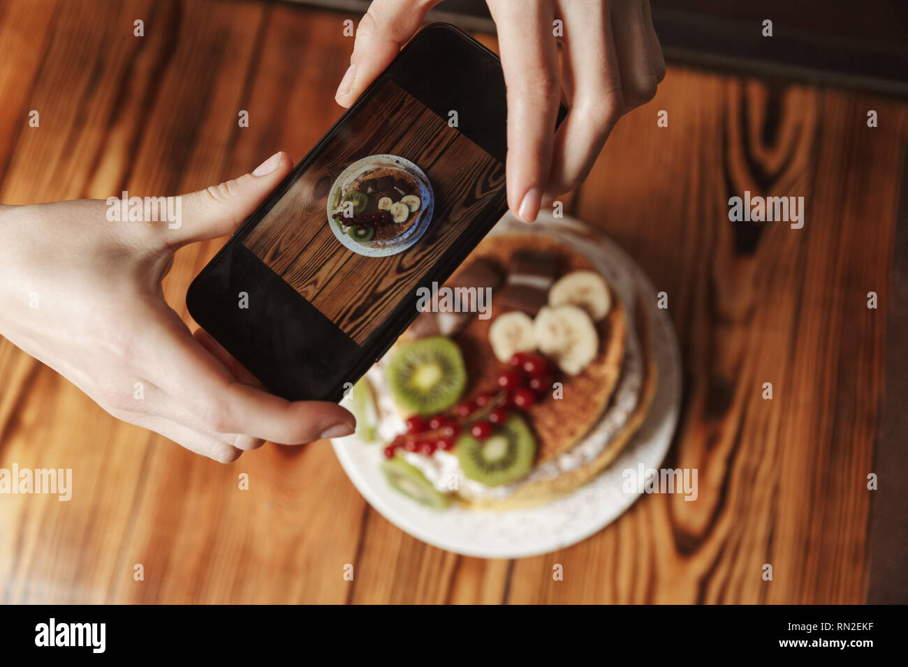 Close up of a woman taking a photo de crêpes aux fruits et crème sur une table Banque D'Images