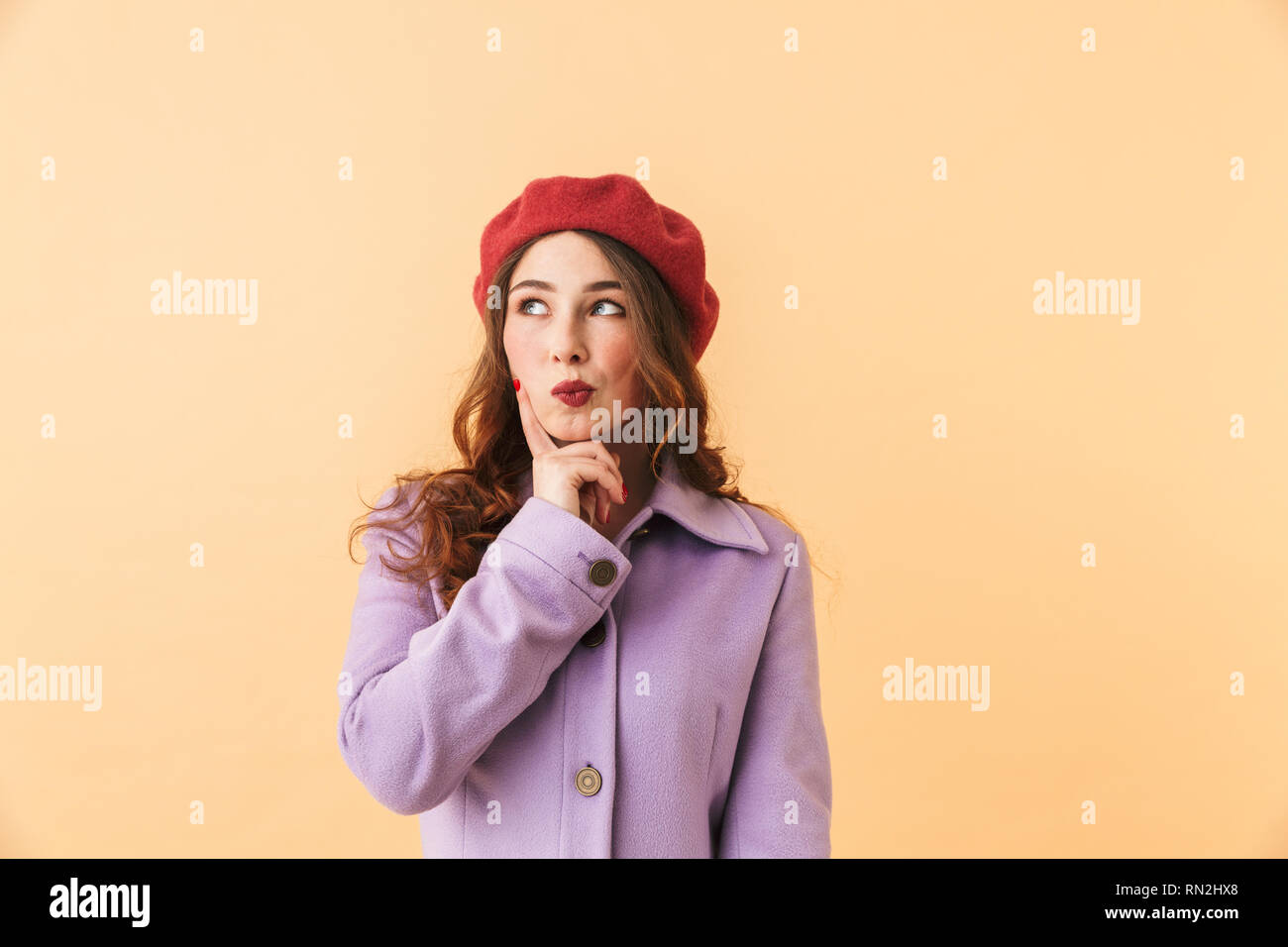 Portrait de fille brune 20s en manteau et hat smiling while isolés sur fond beige Banque D'Images