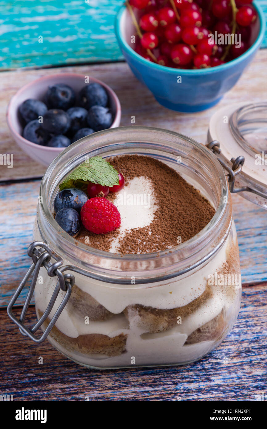 Tiramisu dessert savoureux dans un bocal en verre sur la table de couleurs Banque D'Images