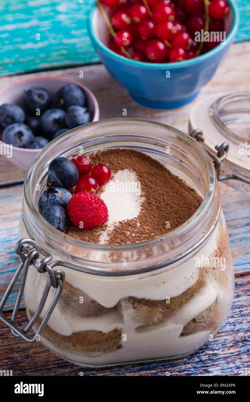 Tiramisu dessert savoureux dans un bocal en verre sur la table de couleurs Banque D'Images