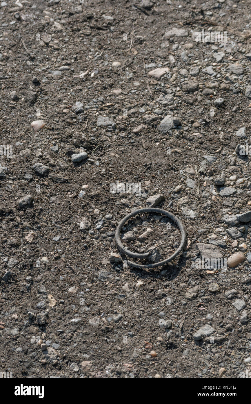 Morceau de câble en caoutchouc enroulé autour dans un cercle vu sur un sentier du sol. Métaphore cercle intérieur. Banque D'Images