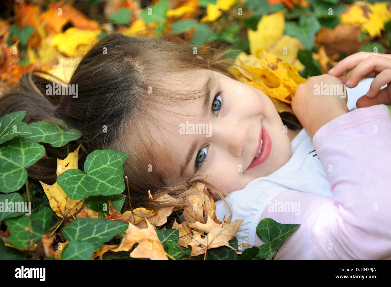 Petite fille s'amuse à jouer dans les feuilles d'automne de l'Est du Tennessee. Elle est tenue d'une et regardant la caméra de son ventre suis Banque D'Images