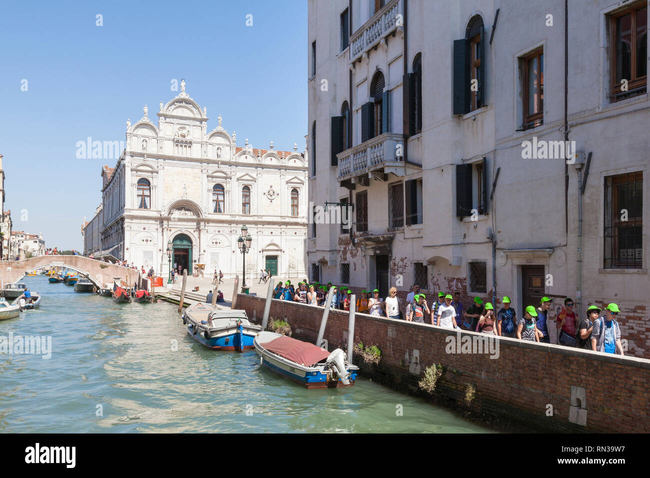 Tour group walking through Castello, Venise, Italie sur un canal en face de Campo dei Santi Giovanni e Paolo et Scuola Grande di San Marco Banque D'Images