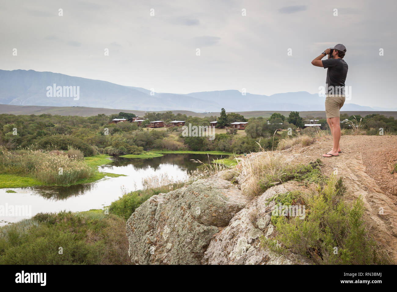 Un jeune homme cherche des oiseaux le long de la rivière Breede, Parc National de Bontebok, Western Cape, Afrique du Sud, où l'observation des oiseaux et la randonnée sont populaires. Banque D'Images