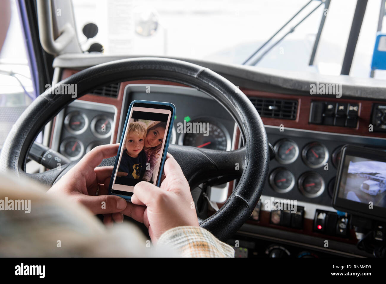 Mains de camionneur holding smart phone avec photo de ses enfants Banque D'Images
