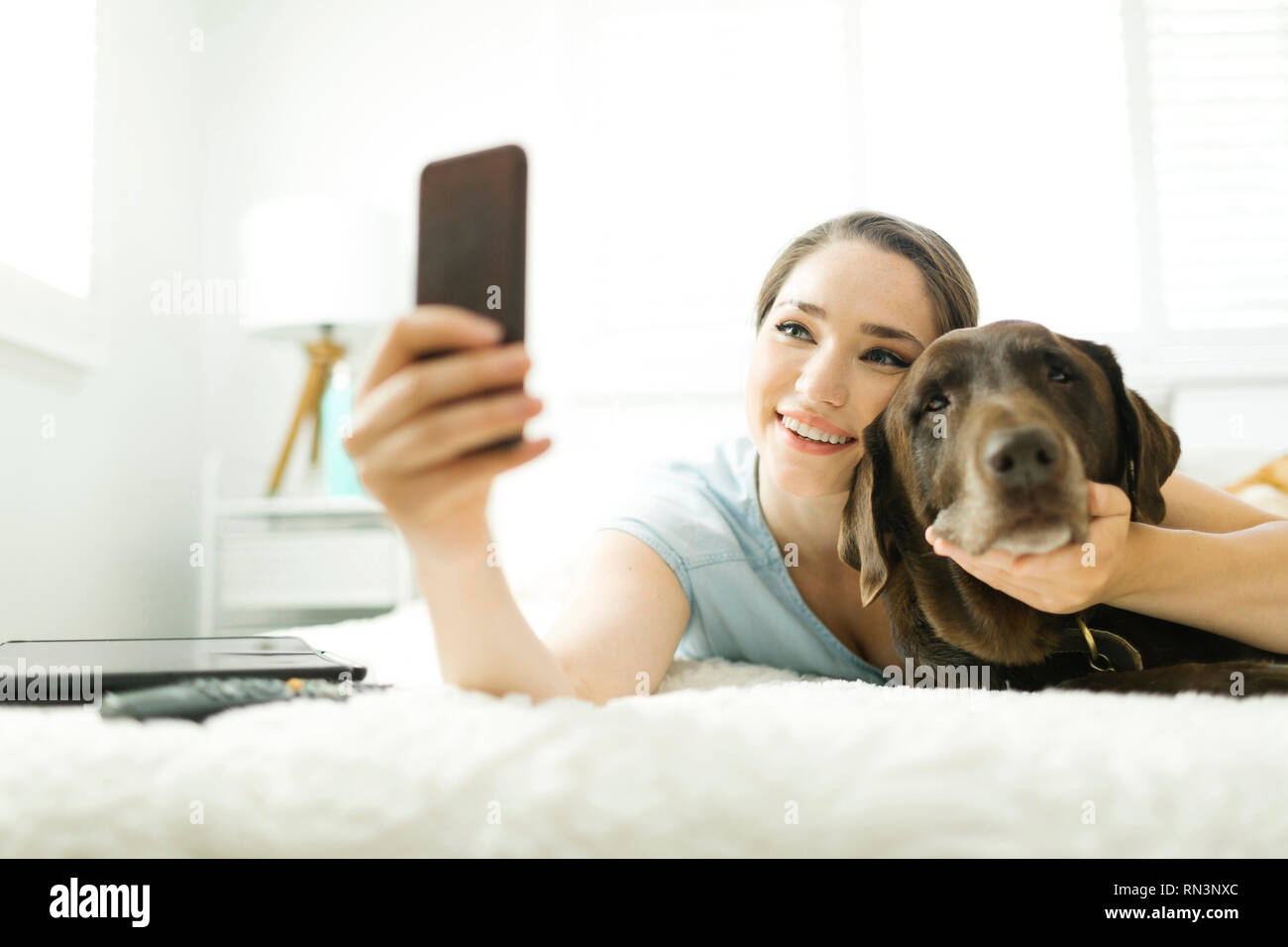Jeune femme en tenant avec chien selfies Banque D'Images