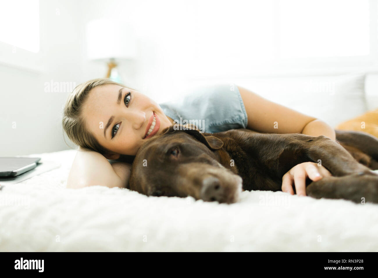 Souriante jeune femme couchée avec son chien de compagnie Banque D'Images