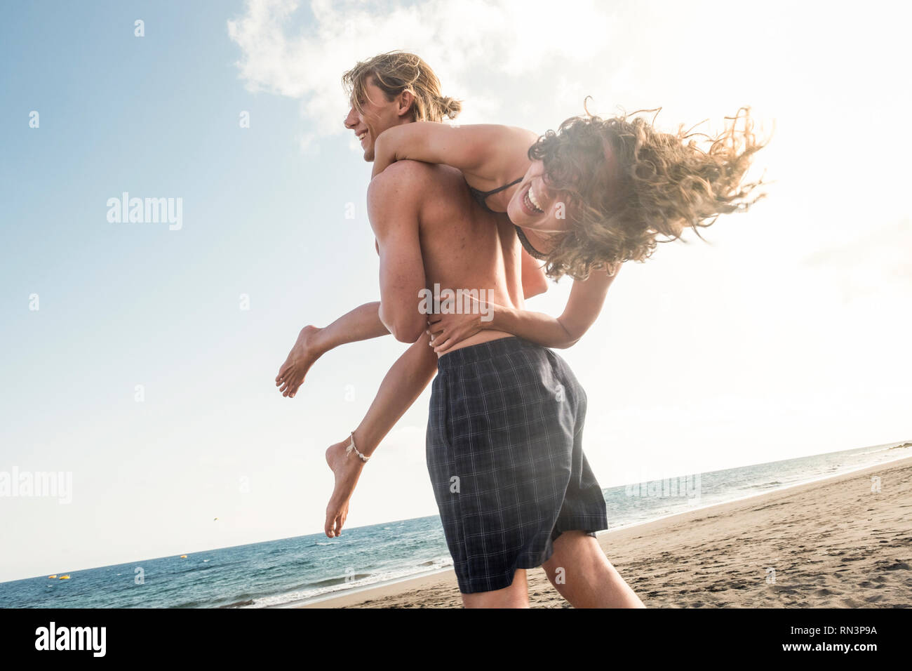 Cheerful couple beaucoup ri avec bonheur tandis que l'homme porter la femme  sur son épaule comme un sac d'été - vacances à la mer, concept Photo Stock  - Alamy