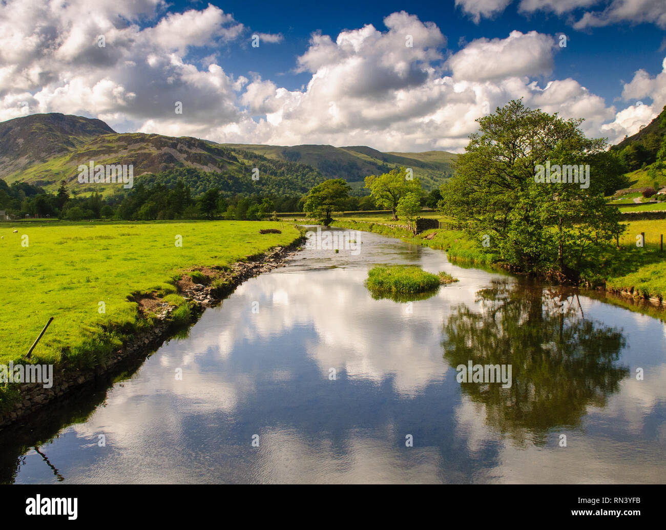 Goldrill Beck rivière coule à travers les champs des terres agricoles dans la vallée de l'Angleterre Ullswater Lake District, avec Glenridding Dodd montagne derrière. Banque D'Images