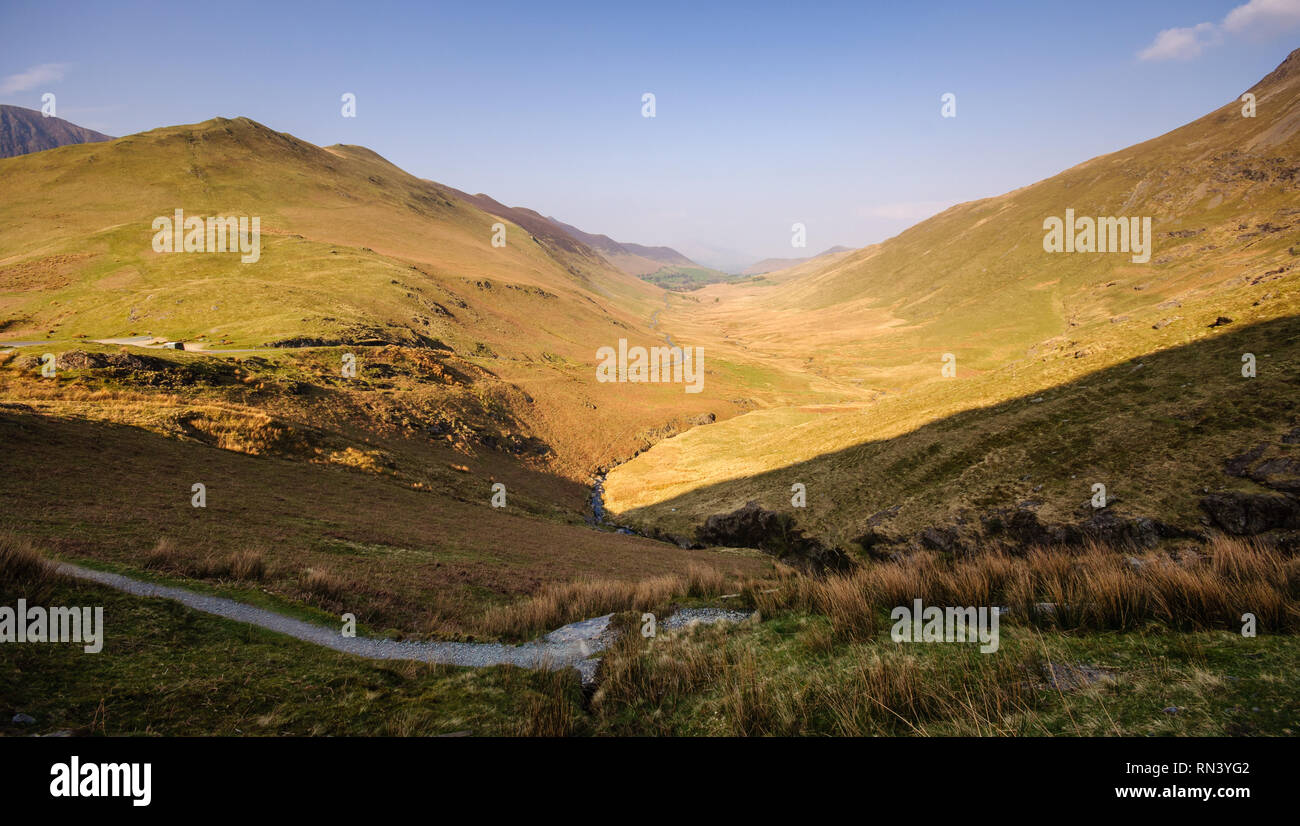Un étroit chemin de campagne monte par la lande de montagne dans la vallée de Newlands en Angleterre's Lake District National Park. Banque D'Images