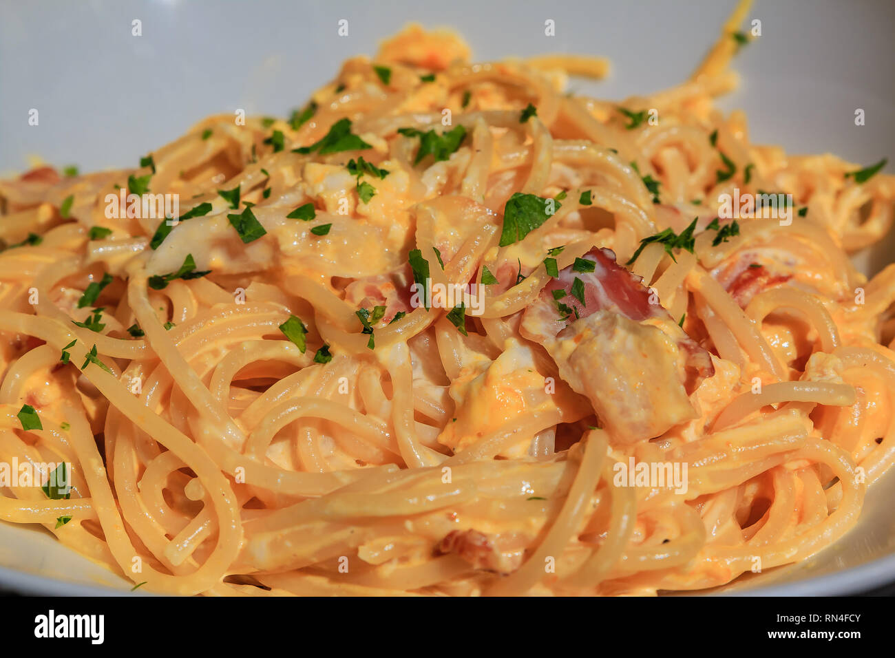 Vue rapprochée d'un délicieux plat de spaghetti carbonara italienne fraîchement préparés avec du jambon, des œufs et le parmesan, garnie de basilic dans une petite res rustique Banque D'Images