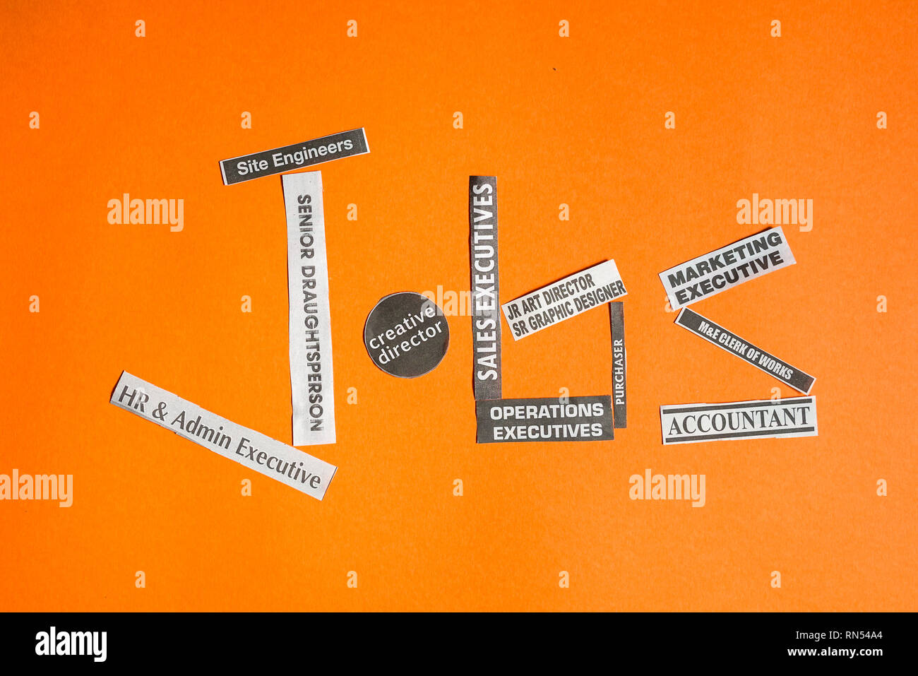 Emplois ou carrières concept : les titres des emplois ou professions coupé de papier journal pour faire le mot emploi, sur fond orange Banque D'Images