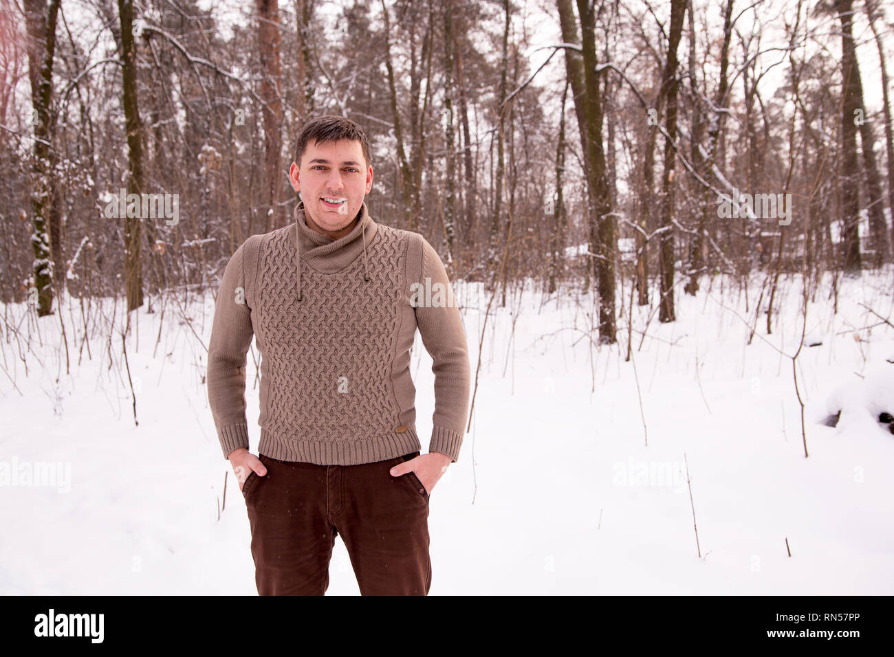 L'homme dans un pull en hiver dans les bois. l'homme dans la forêt d'hiver fait une photo sur le téléphone. Banque D'Images