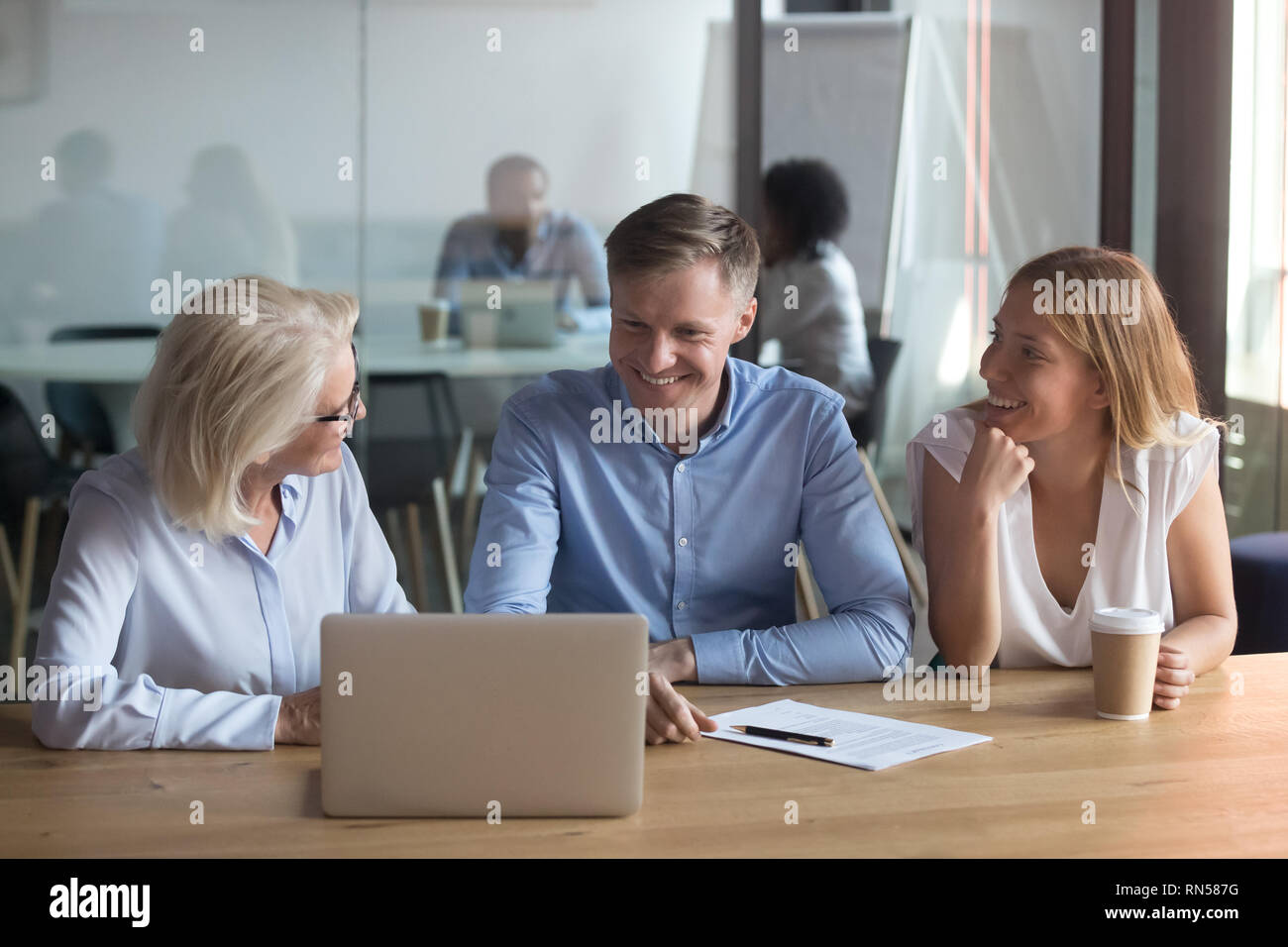 Employés assis dans espace de coworking travailler ensemble à l'aide d'ordinateur portable Banque D'Images