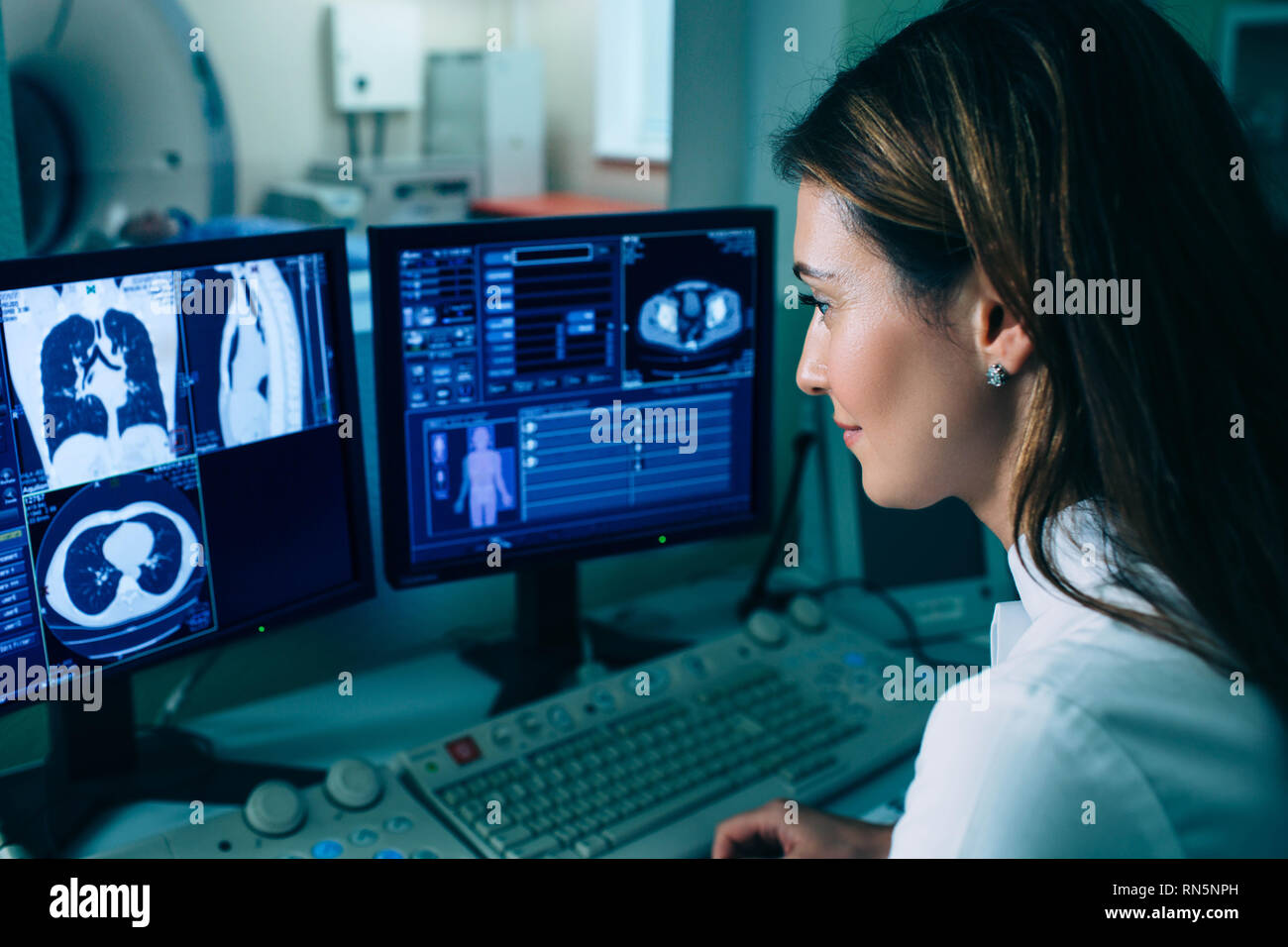 La lecture d'un radiologue CT scan. Femme médecin exécutant CT scan à partir de la salle de contrôle à l'hôpital Banque D'Images