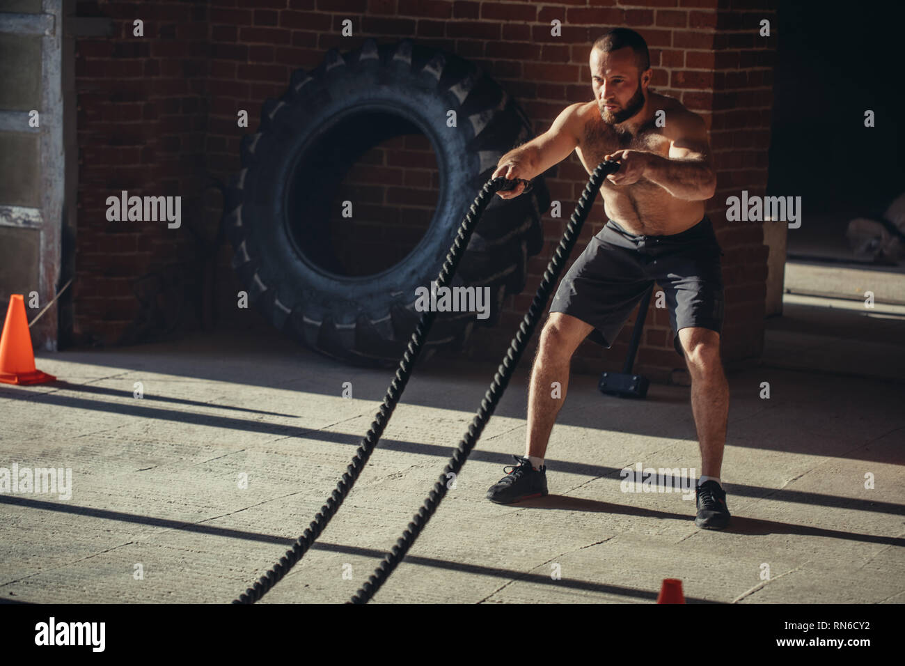 Le travail acharné de l'origine ethnique caucasienne de l'instructeur Crossfit prouve que la formation des cordes sont un entraînement très dynamique qui accélère le pouls du sportif alors que l'al. Banque D'Images