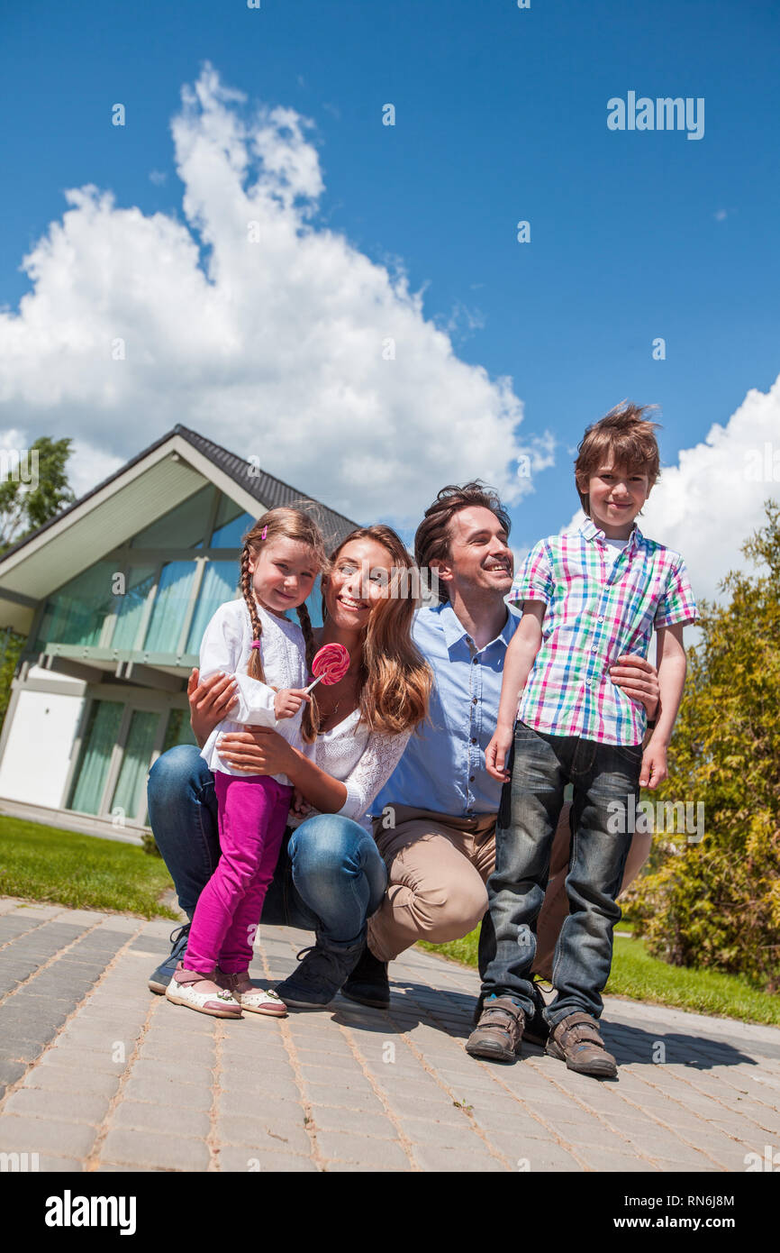 Heureuse famille des parents et d'enfants devant leur maison à l'extérieur Banque D'Images