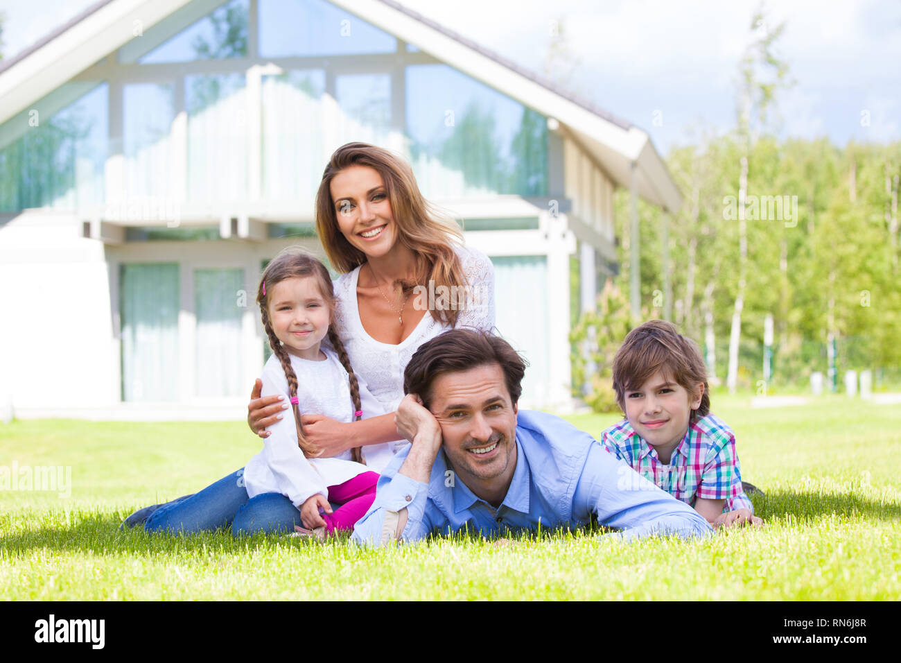 Heureuse famille des parents et d'enfants devant leur maison à l'extérieur Banque D'Images