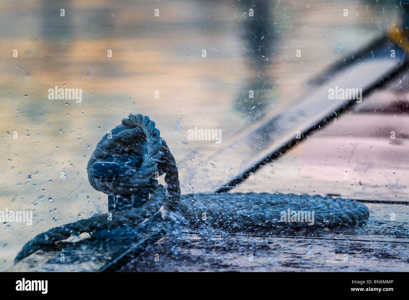 La ligne d'amarrage en spirale enroulée autour de taquet sur un ponton au soir de pluie. Banque D'Images