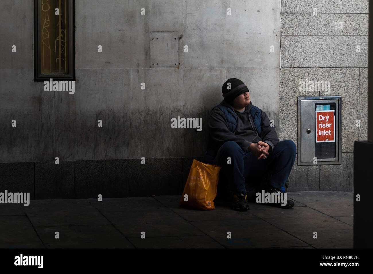 Homme assis seul dans l'arc et à la recherche vers le soleil. Espoir de sombre à feux. Banque D'Images