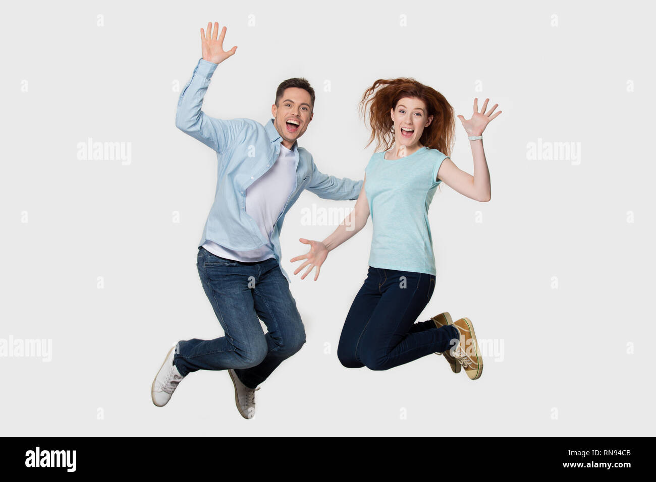 Heureux heureux jeune couple amis sautant ensemble isolé sur fond Banque D'Images