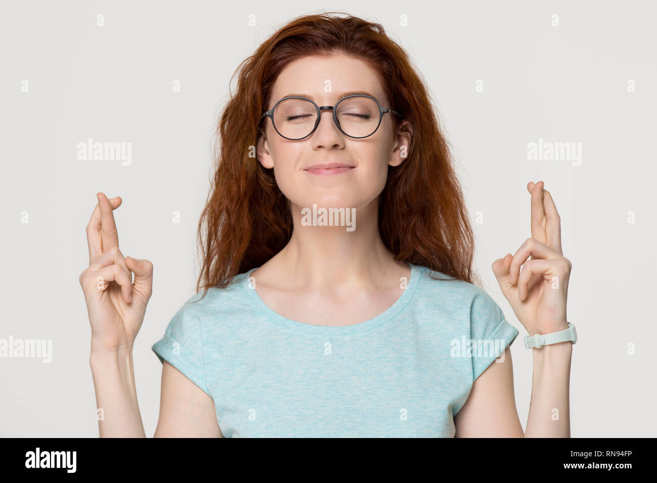 Femme rousse superstitieux crossing fingers qui souhaitent bonne chance pour Banque D'Images