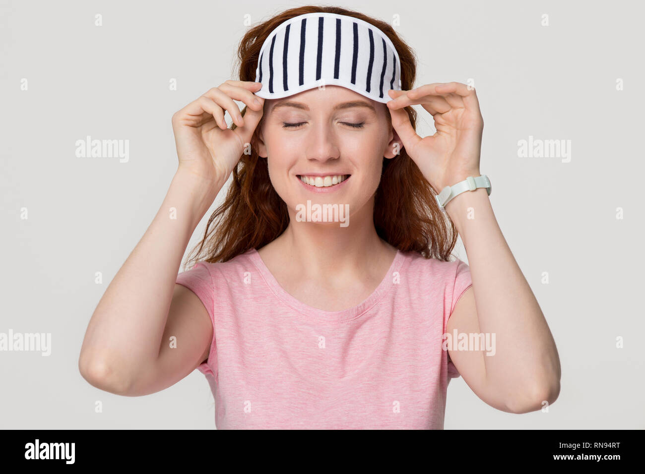 Smiling young redhead femme portant ce masque de sommeil à rayures Banque D'Images