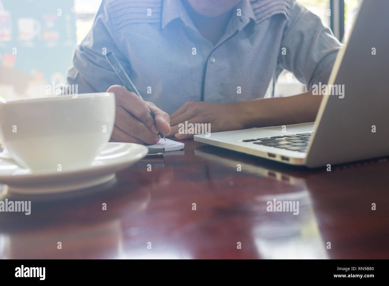 La photo en gros du jeune homme écrit en notes Banque D'Images