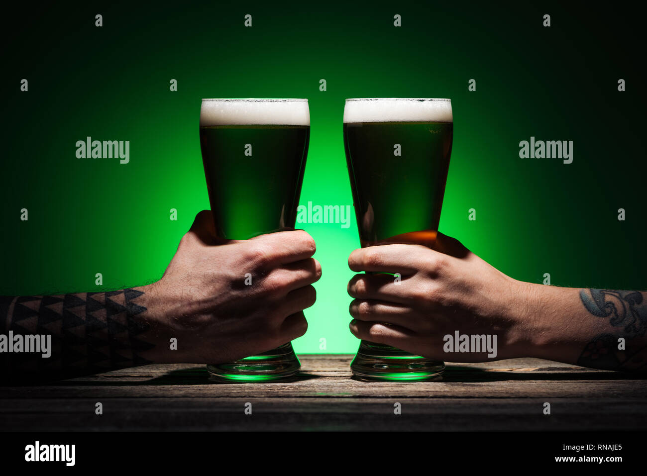 Portrait d'hommes tenant des verres de bière irlandaise sur fond vert Banque D'Images