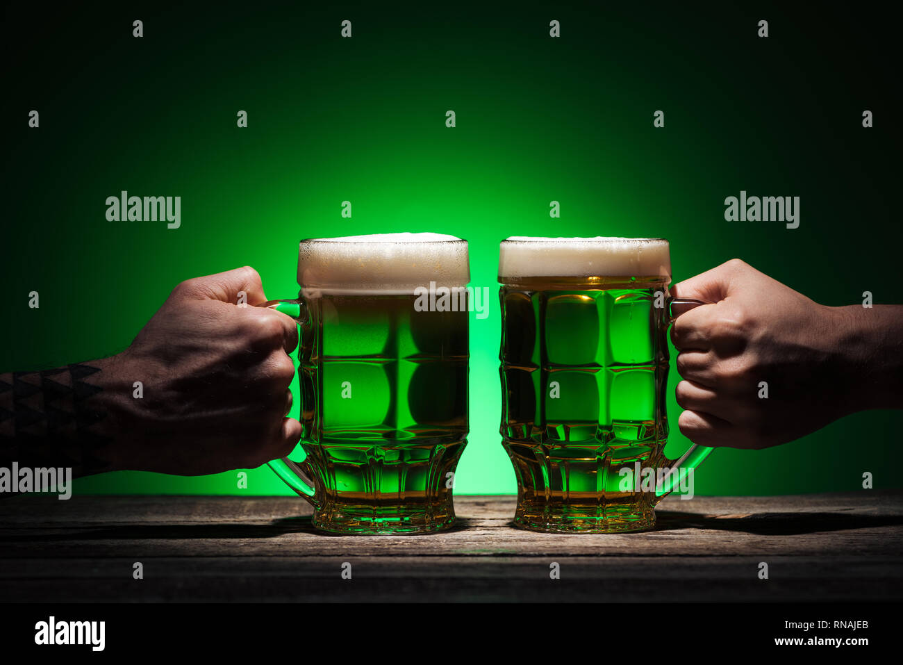 Portrait d'hommes occupant des verres d'ale sur fond vert Banque D'Images